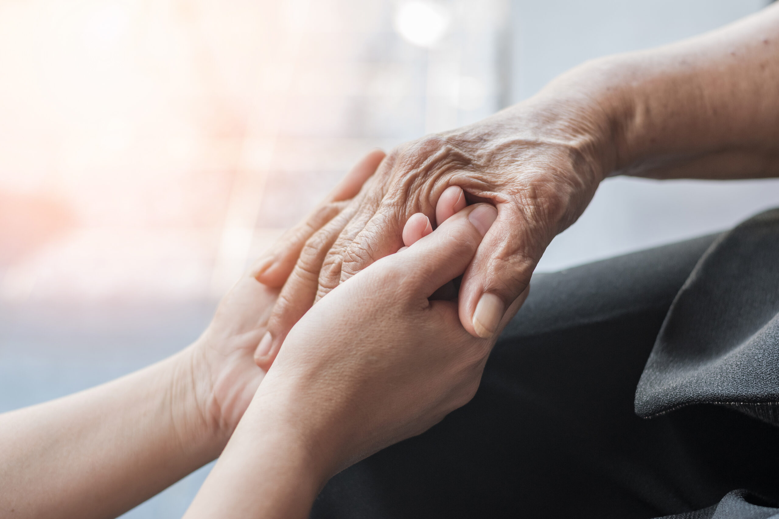 Senior holding hands with relative in Memory Care Apartments.