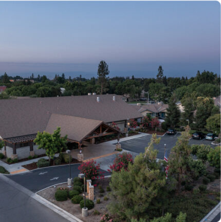 Community center surrounded by trees and parking lot under a twilight sky. No recognizable landmarks or historical buildings are visible.