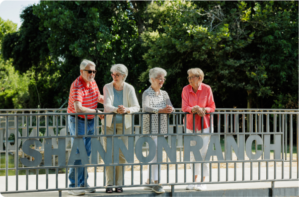 Four people stand by a railing labeled "SHANNON RANCH," surrounded by lush greenery on a sunny day, appearing relaxed and cheerful.