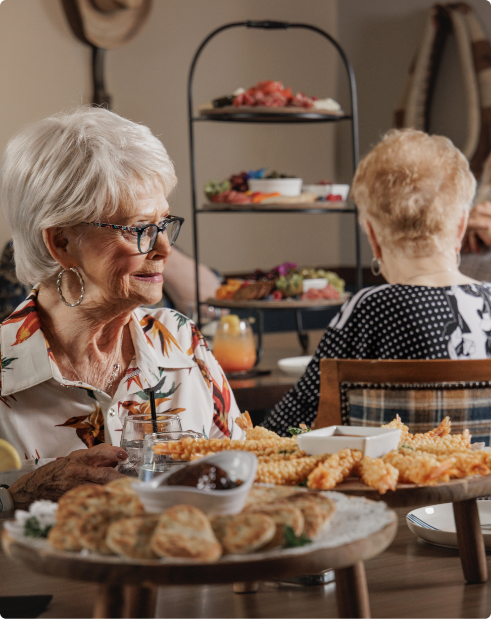 Two people dining at a restaurant with a table of assorted appetizers and drinks, creating a warm, social atmosphere.